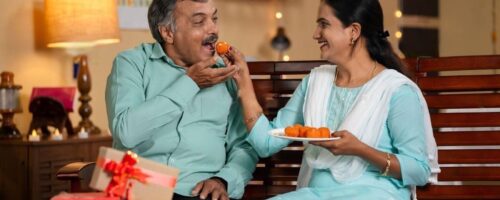 daughter-and-father-eating-sweets-by-sharing-together-at-home-during-diwali-festival-celebration-at-home